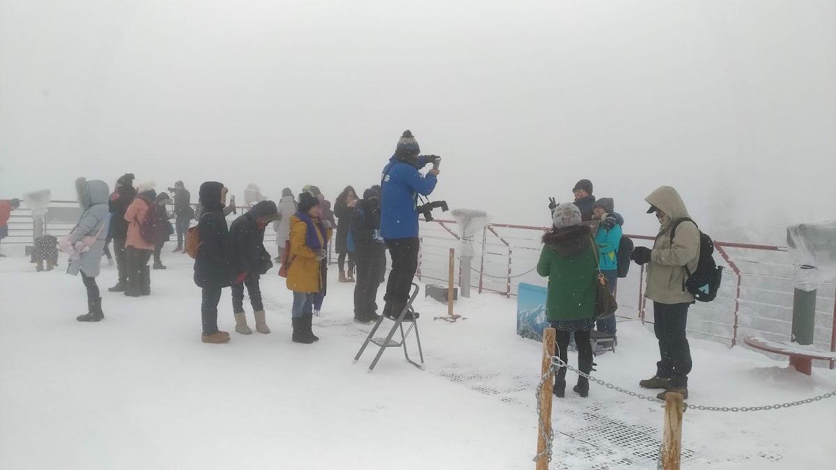 大雪紛飛的山頂觀景台上遊客拍照