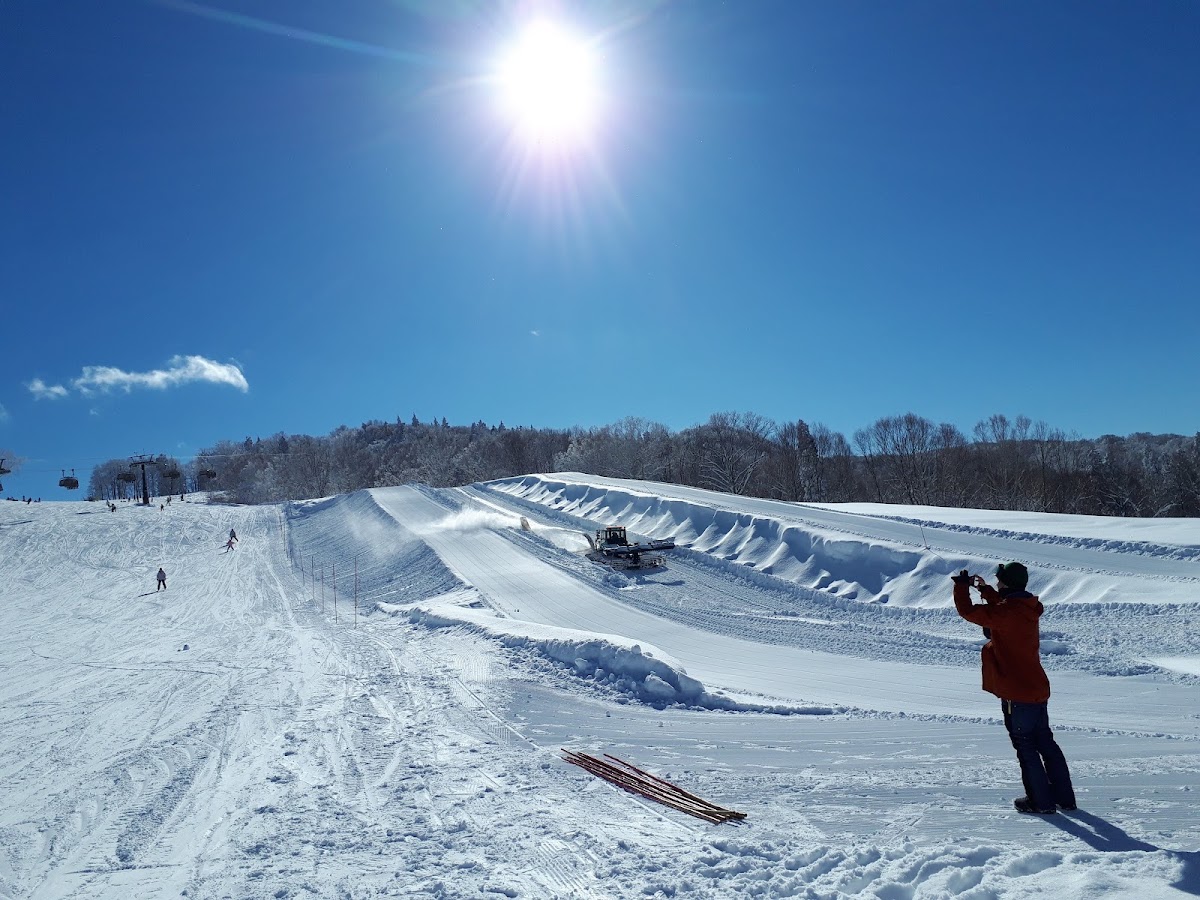 陽光明媚的滑雪場與壓雪車作業