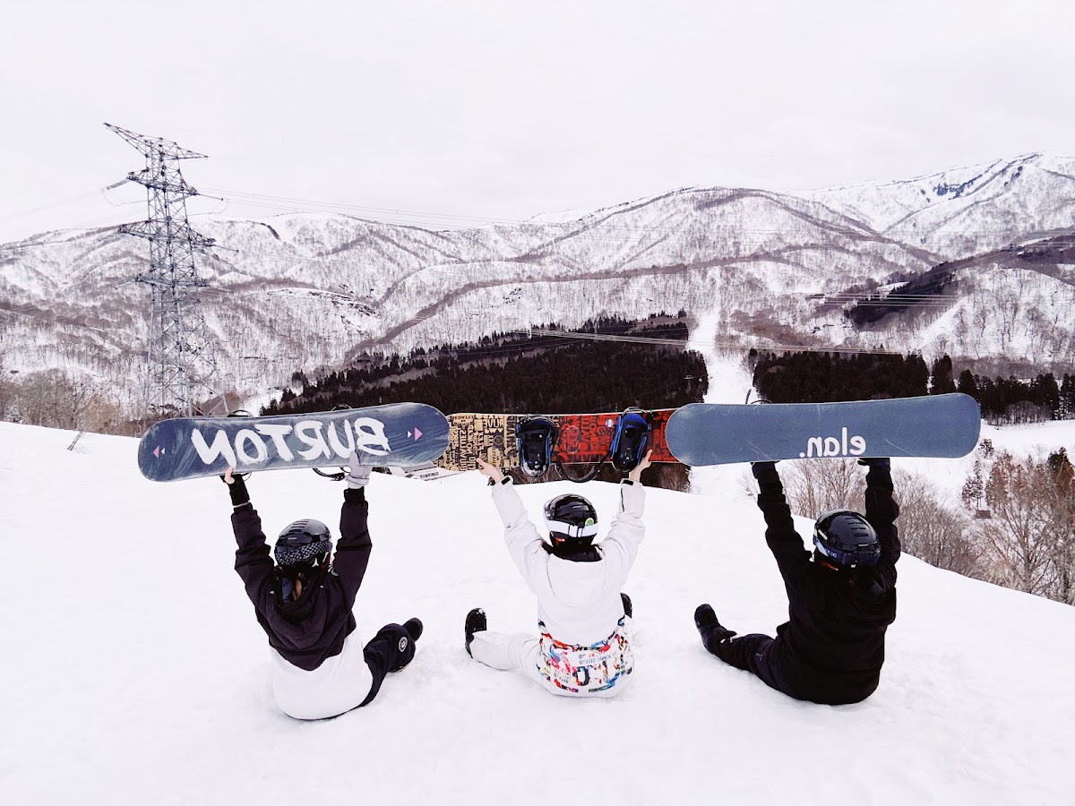 三位滑雪者坐在雪地上舉起滑雪板合影