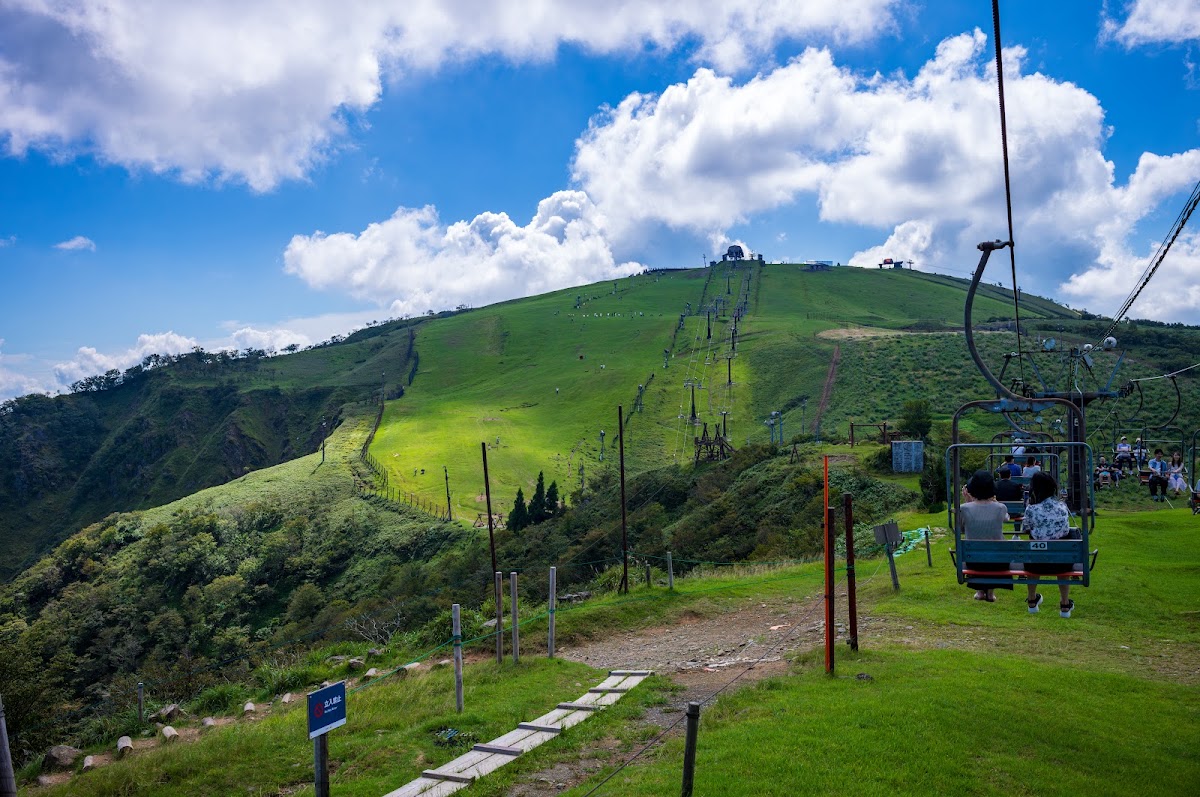 搭乘登山吊椅俯瞰綠意山坡與纜車