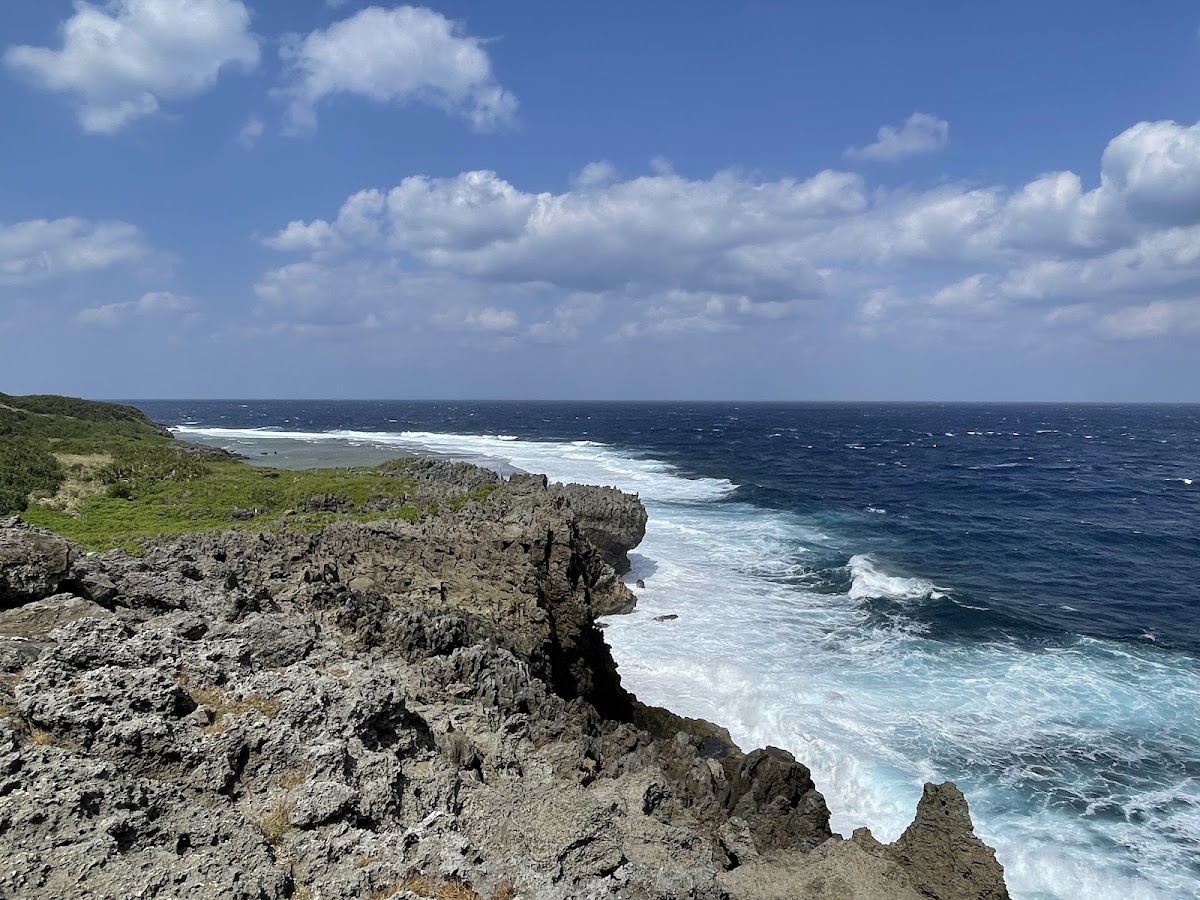 陽光下的海岸礁岩與藍天白雲海景